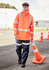 A heavy-duty waterproof jacket in fluorescent orange with reflective strips, worn by a model in blue work pants.