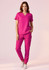 A women's pink v-neck scrub top paired with matching pink scrub pants, featuring pockets and a logo.