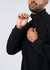 A man in a black polar fleece half zip top, adjusting the zip at the collar. The top features a logo.
