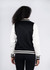 A black and white women's varsity jacket with a soft shell design, featuring a logo on the back.