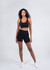 High rise legging shorts in black on a model, paired with a matching black crop top. The outfit features a logo.