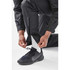 Men's Olympia Rain Pant in black, featuring adjustable leg cuffs, being worn with a black sneaker and white socks.