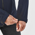 A close-up of a person's hand adjusting the cuff of a navy blue rain jacket. The jacket features a branding logo.