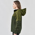 A woman models a green Women's Vertex Stormshell jacket with a hood and a logo on the chest.