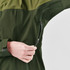 A hand zips up a green women's jacket featuring a dual-tone design with a darker upper section.