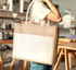 A jute tote bag with a white pocket, featuring sturdy handles and a natural colour design.