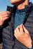 A navy puffer vest being worn, with a person adjusting the zip, layered over a blue top.