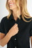 A black short sleeve shirt with a button-up front features a woman smiling while adjusting the collar.