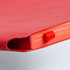 A medium-sized red notebook with a ribbon bookmark peeking out from the spine and a smooth cover finish.