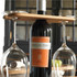 A wine bottle carrier with a bamboo top, holding a wine bottle and two glass stems. The glasses are clear and elegant.
