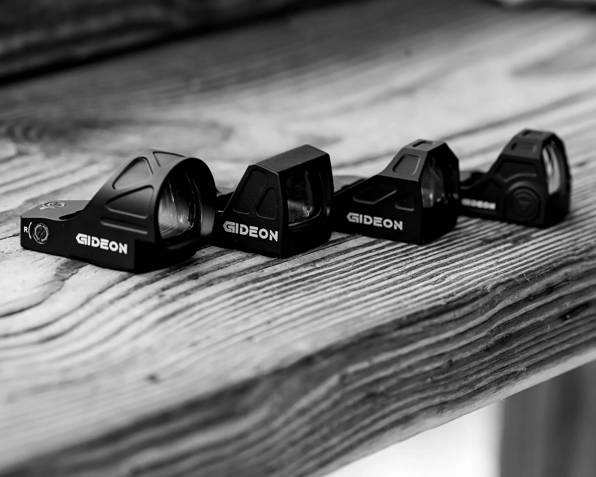 Four Gideon optics displayed on a wooden table