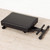 Tiger padded keyboard bench folded flat, black cushioned seat with metal legs folded underneath on a wooden floor.