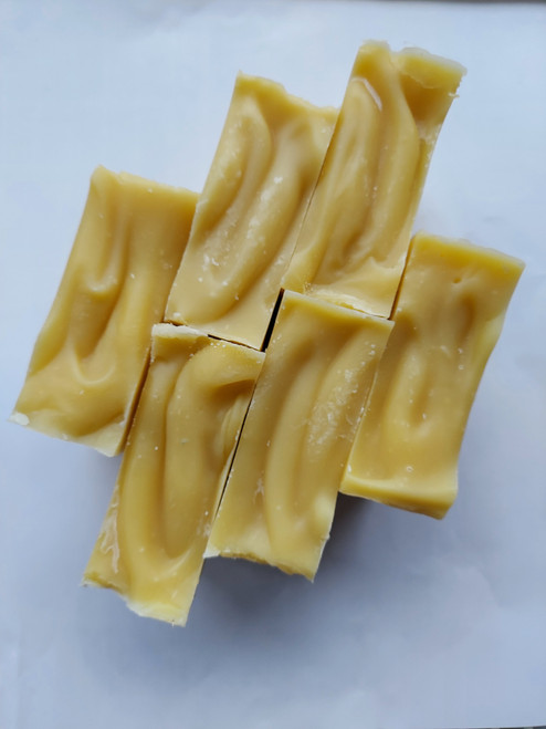 Image shows a top view of six bars of soap. Soap is a light orange color, and it has a grooved texture.