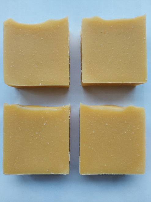 Image shows a side view of 4 bars of soap. Soap is a light orange color.
