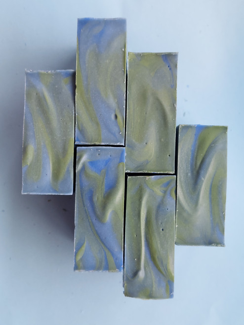 Image shows top view of six bars of soap. 
Soap tops have blue and green swirls, and a slightly grooved texture.