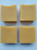 Image shows a side view of 4 bars of soap. Soap is a light orange color.