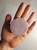 Image shows a circular shaped, lavender color scrub bar being held in a person's hand.