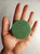 Image shows a green circular scrub bar being held in a person's hand.