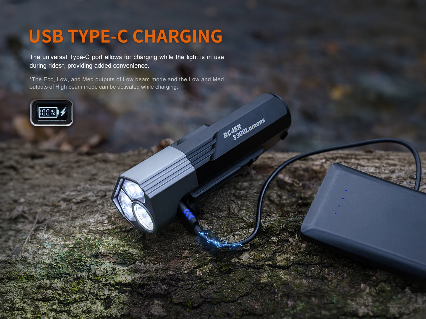 Fenix BC45R bicycle light charging via USB Type-C from a power bank on a tree stump.