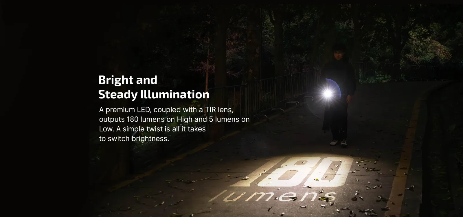 Person using the Olight i17 Checkered Flag Limited Edition Rechargeable Keychain Light to illuminate 180 lumens on a path at night.