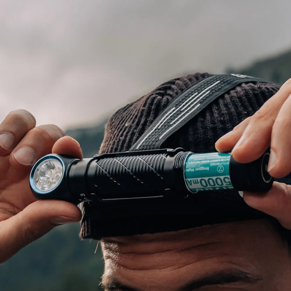 Hands replacing the 5000mAh battery in the Olight Perun 3 High Performance 3000 lumen rechargeable headlamp.