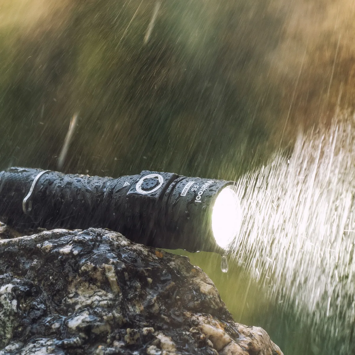 Weltool F5 flashlight shining brightly on a wet rock, with rain falling, demonstrating its waterproof capability.