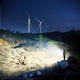 Acebeam EC20 - 2800 Lumen EDC Torch with RGB illuminating a path at night with wind turbines.
