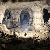Person exploring a vast cave with the powerful beam of the Acebeam X80GT 3 - 30000 Lumen High-Power Exploration Torch.
