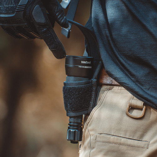 Weltool T10-HG Devil Incarnate flashlight carried in a black holster on a person's belt.