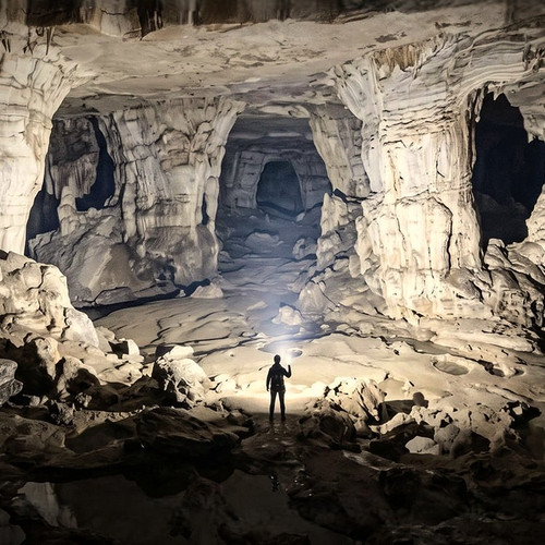 Person exploring a vast cave with the powerful beam of the Acebeam X80GT 3 - 30000 Lumen High-Power Exploration Torch.