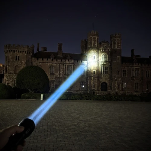 Acebeam W10 Pro - 1425m Long-Range LEP Torch in use, shining its powerful beam onto a distant castle at night.