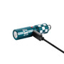 Olight i17 Checkered Flag Limited Edition Rechargeable Keychain Light being charged with a USB cable, showing a red indicator light.