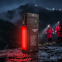 Acebeam X35 flashlight standing upright outdoors at night, with its side panel glowing red and two figures in the background.
