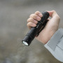 Hand holding the Wuben L3 3000 lumens EDC tactical flashlight in the rain, demonstrating water resistance.