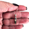 Labradorite crystal point sterling silver necklace in my hand.  Labradorite crystal point sterling silver necklace in my hand.