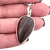 Teardrop-shaped red Tigers Eye sterling silver pendant in my hand. 