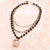 Multi-chain black beaded necklace with a crystal charm and lobster clasp. 