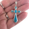 Sterling silver cross pendant with Kingman turquoise and opal geometric inlay, handcrafted in New Mexico, USA in my hand..