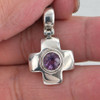 Close-up of amethyst sterling silver cross pendant held in hand, showing gemstone color and polished silver detailing.