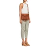 Model wearing the Ampere cognac light brown fringe crossbody purse with adjustable shoulder strap, Western-inspired envelope flap, and long cascading fringe.