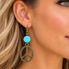 Turquoise Peace Sign Dangle Earring displayed on a blonde model, showcasing a vibrant turquoise-blue bead and large distressed antique bronze-tone peace symbol pendant. Perfect for boho, western, and retro-inspired jewelry styling.