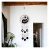 Black and white yin yang capiz shell wind chime hanging indoors against a white wall, showcasing its decorative sun and moon design and cascading shells.