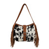 Front view of Myra Bag Loyal West Desert Trail Medium Concealed Carry Shoulder Bag featuring genuine black and white hair-on calfskin, decorative floral tooled leather buckle accent, brown leather shoulder strap, and long Western-style fringe.