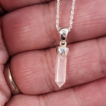 Rose quartz crystal point sterling silver necklace in my hand.  Rose quartz crystal point sterling silver necklace in my hand.