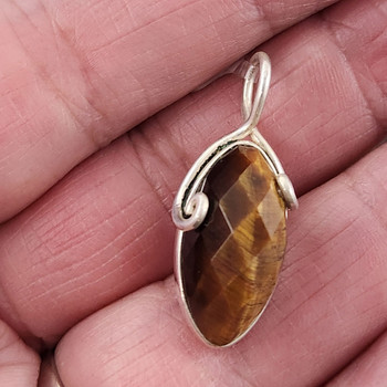 Faceted Tigers Eye sterling silver pendant in my hand. 