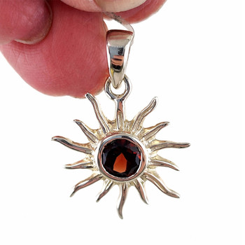 Garnet sterling silver sun pendant dangling from my hand. 