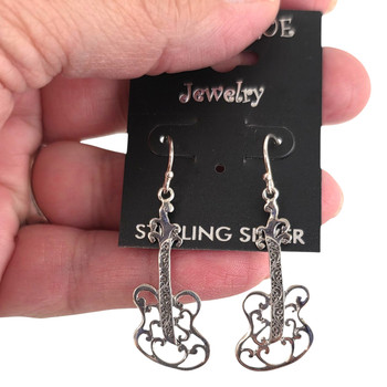 Sterling silver guitar dangle earrings in my hand.. 