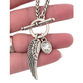 Silver-plated wing and clear crystal charm toggle necklace in my hand. 