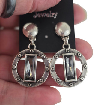 Gray crystal dangle post earrings in my hand. 
