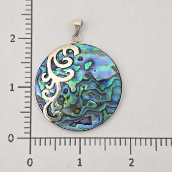 Round paua shell pendant with silver overlay design with a ruler. 